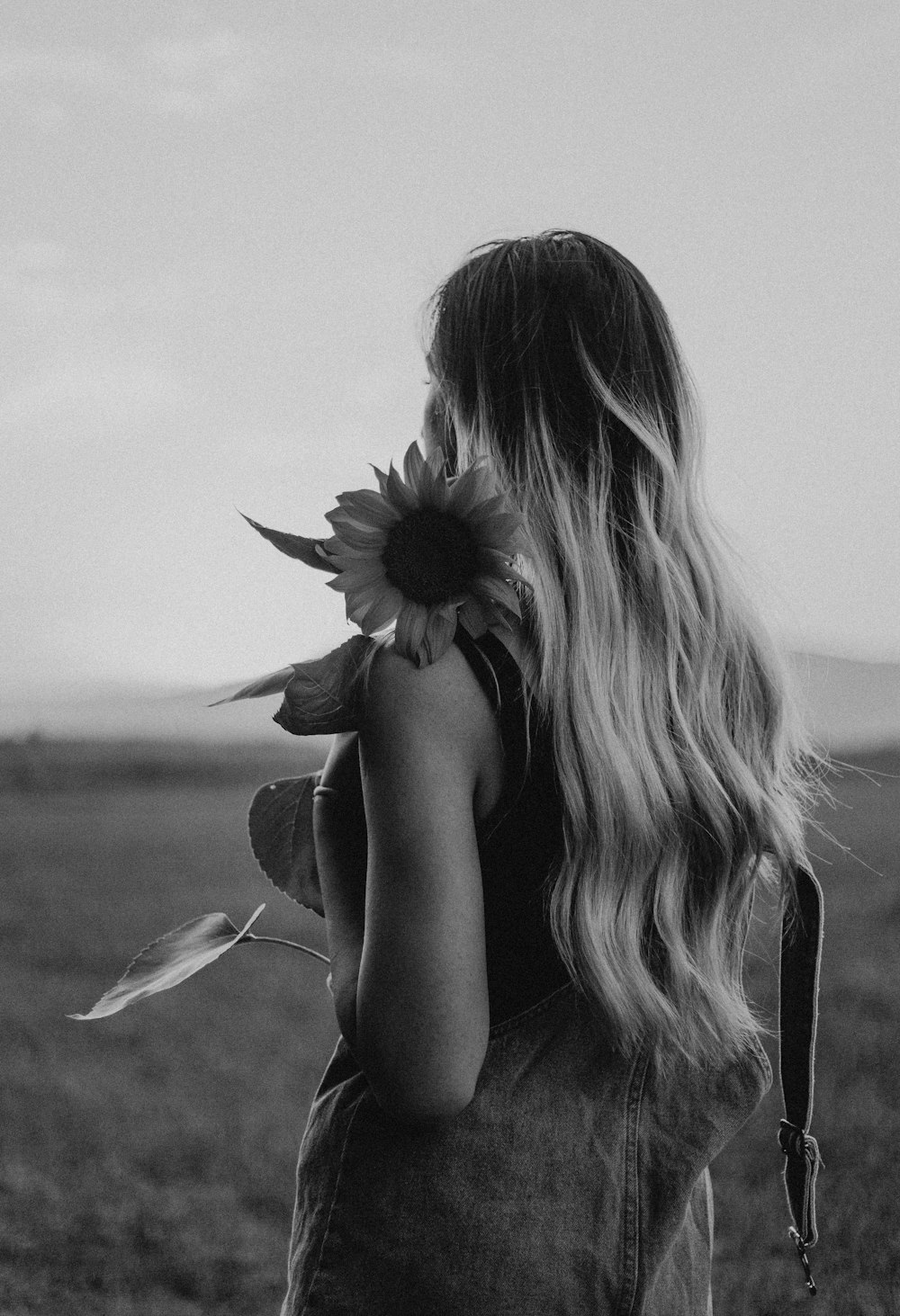 grayscale photo of woman holding sunflower