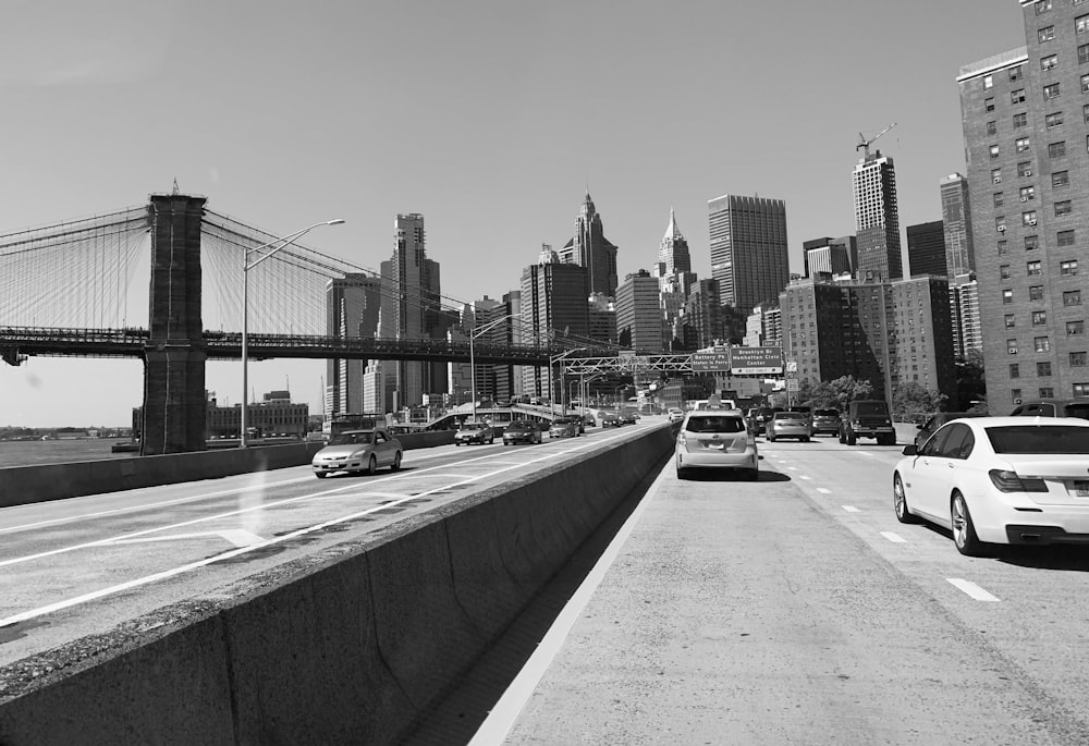 grayscale photo of cars on road near bridge