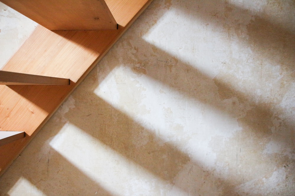 白いコンクリートの壁と茶色の木製階段