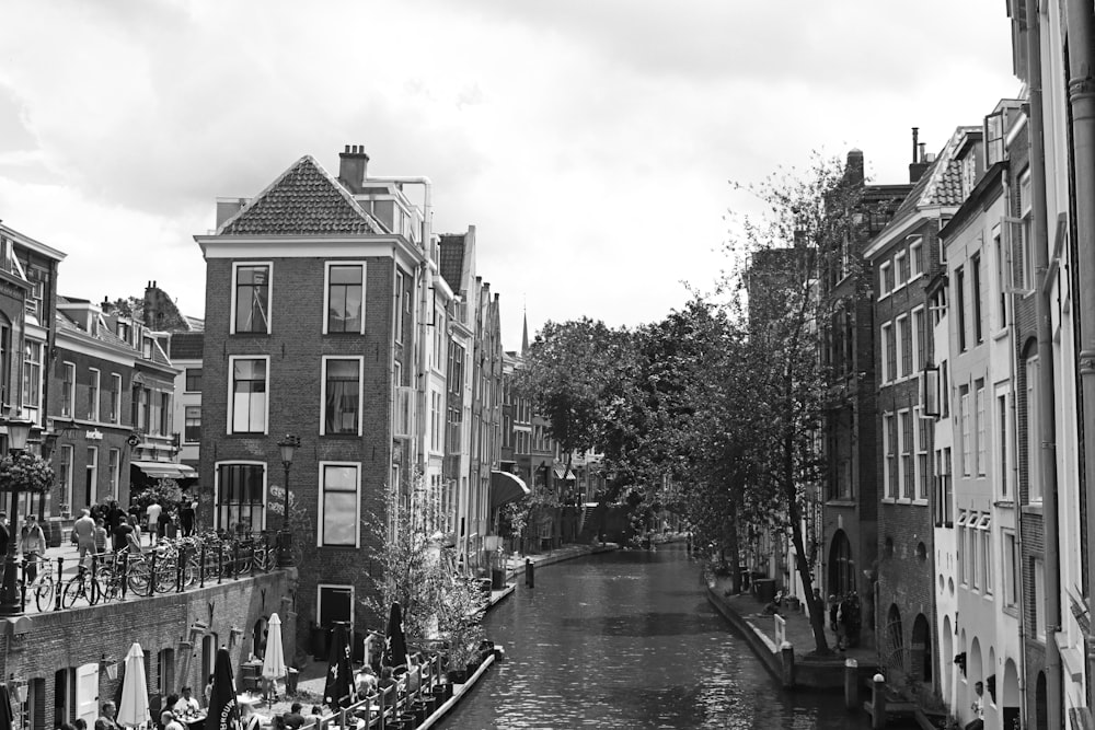 grayscale photo of people walking on street near buildings