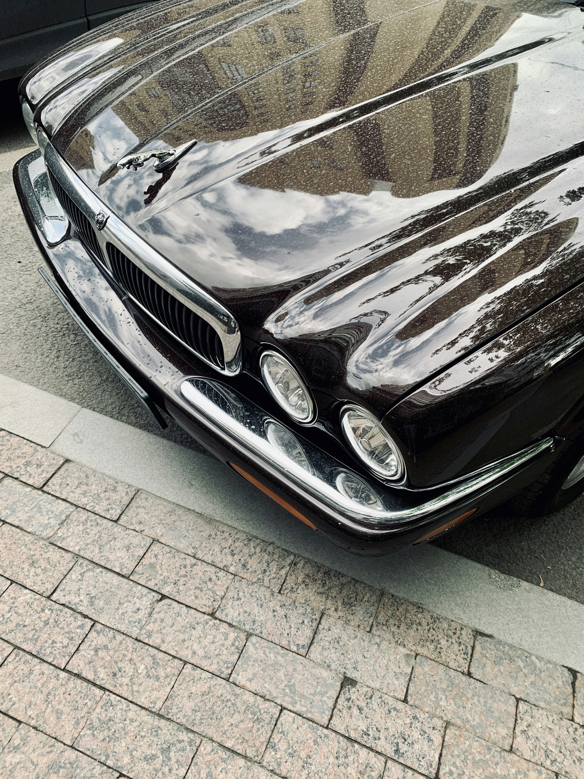 Before-and-after shot of a sleek black car with spotless exterior and gleaming chrome details reflecting the city skyline.