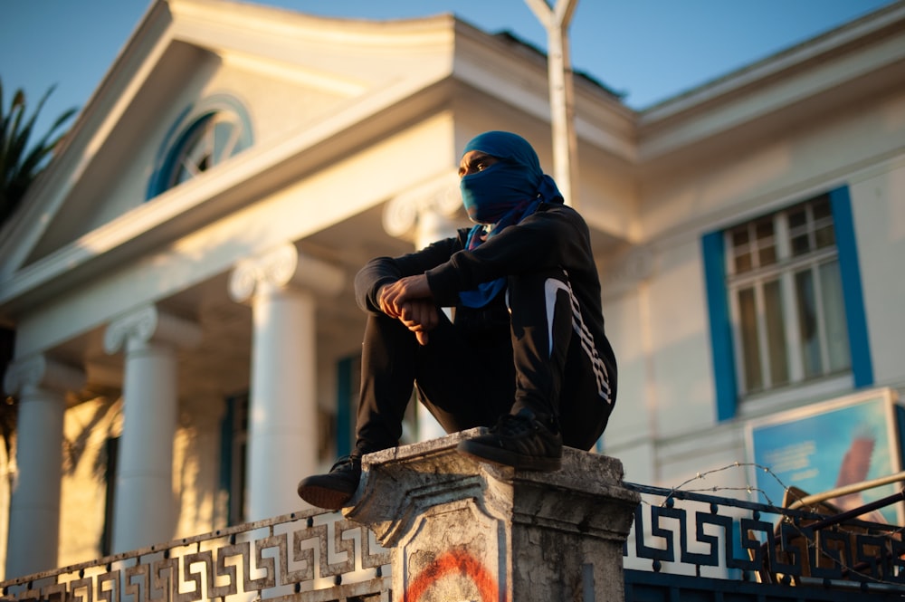 man in black jacket sitting on concrete bench during daytime