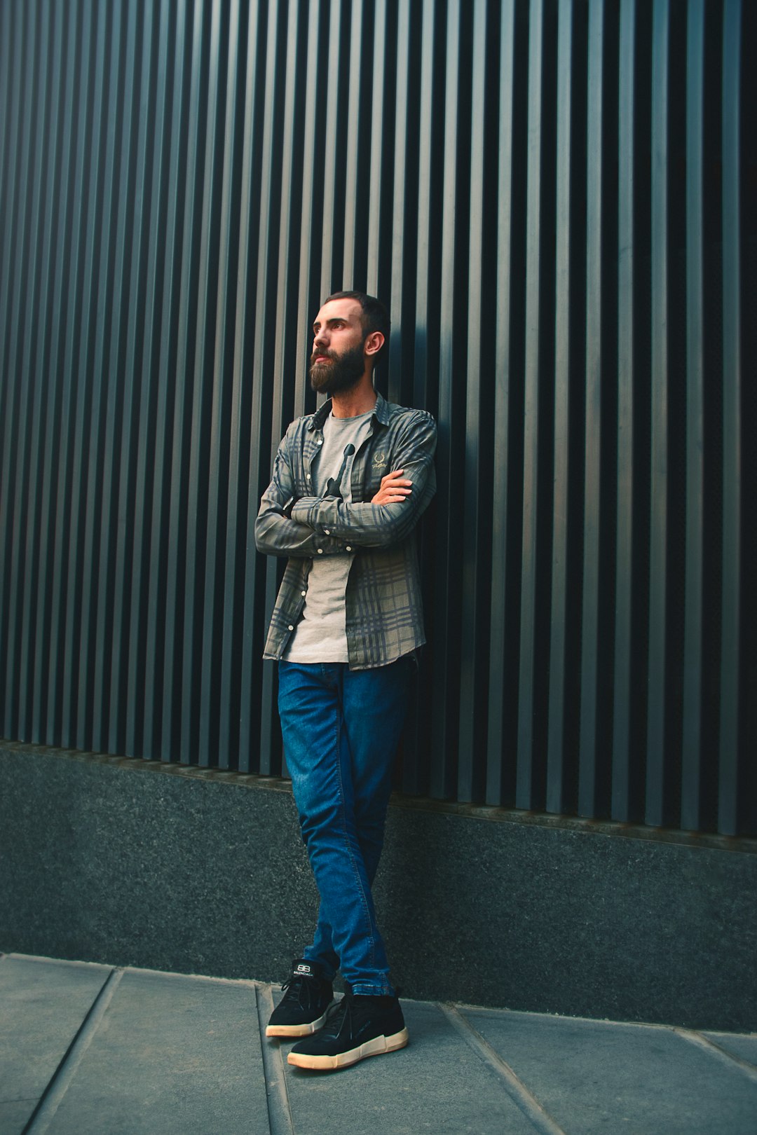 man in blue denim jeans standing beside black wall