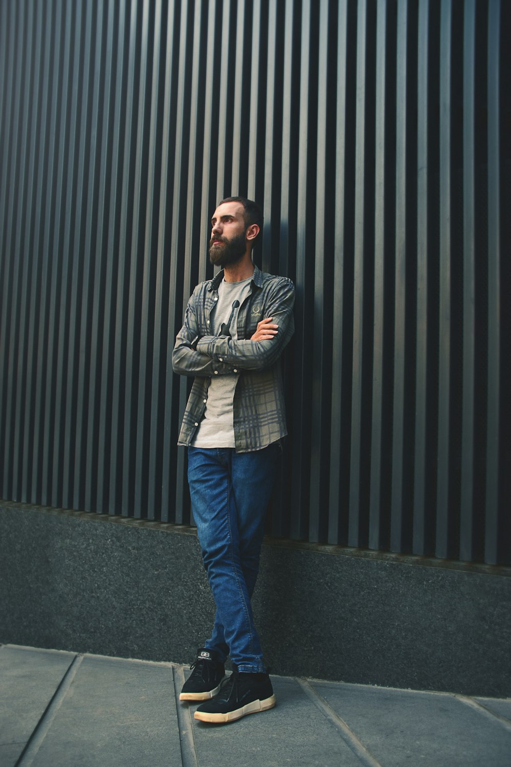 man in blue denim jeans standing beside black wall