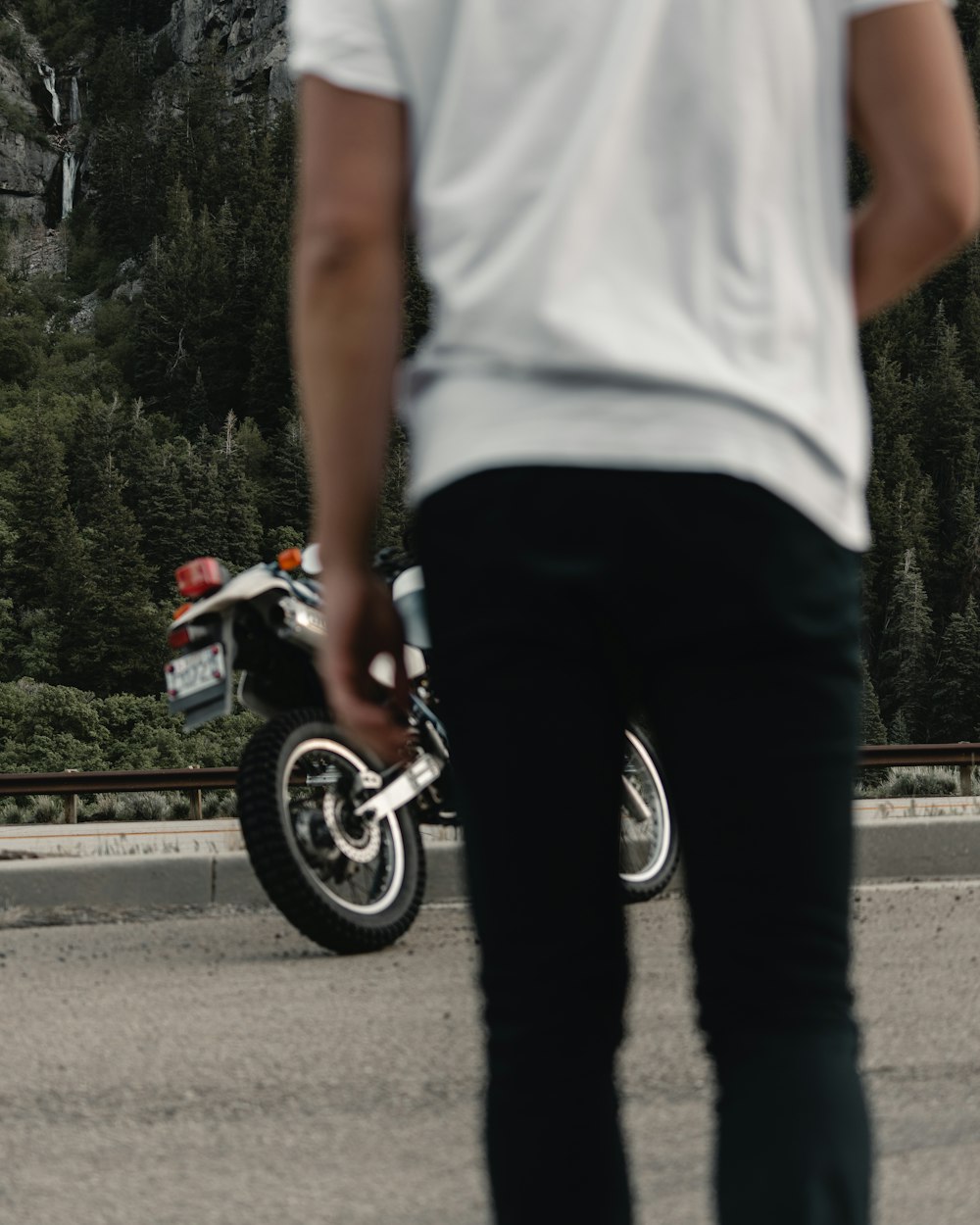 man in white tank top and black pants riding on motorcycle