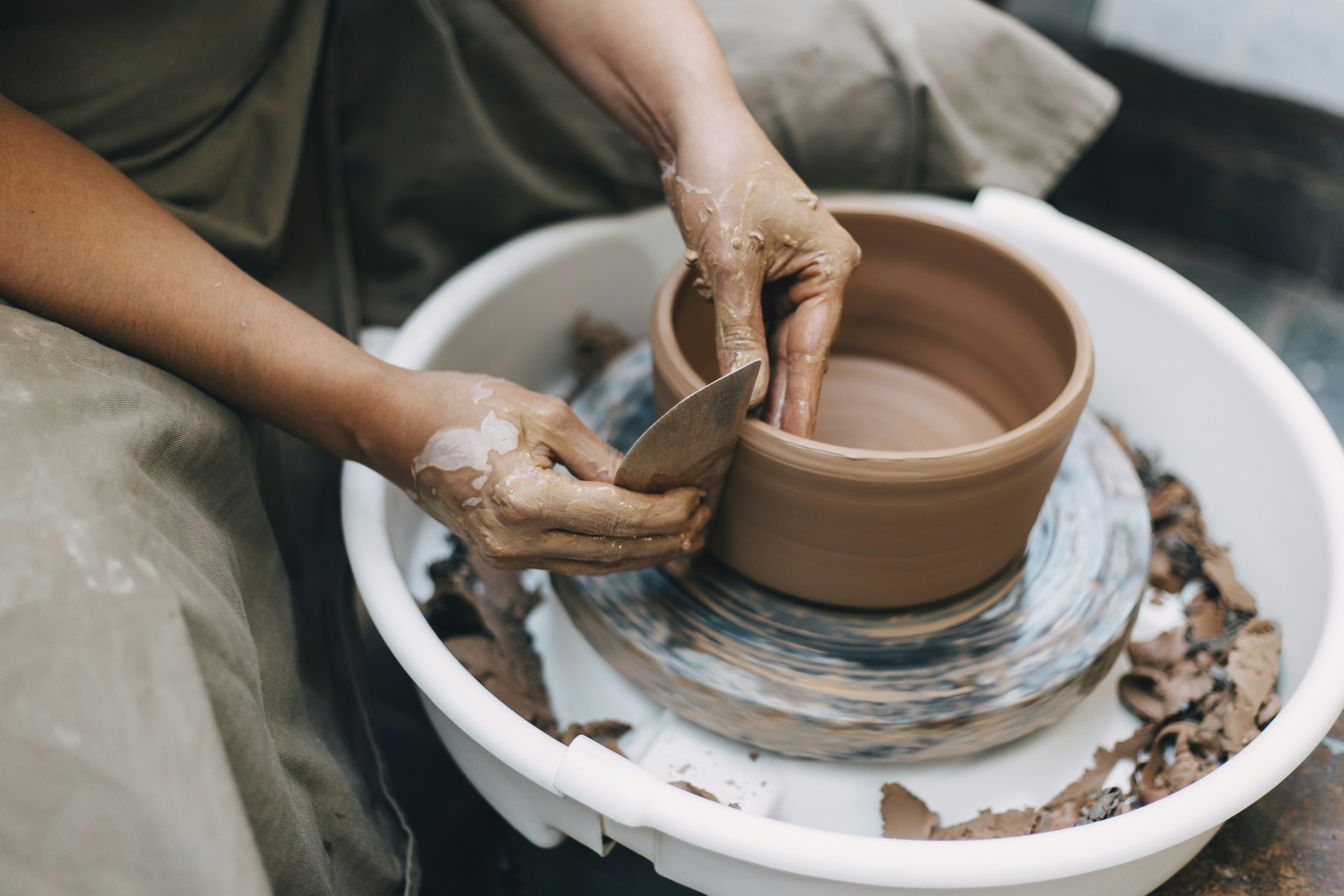 person making clay pot on white round plate