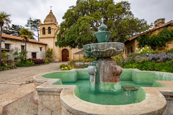 brown concrete fountain near green trees during daytime