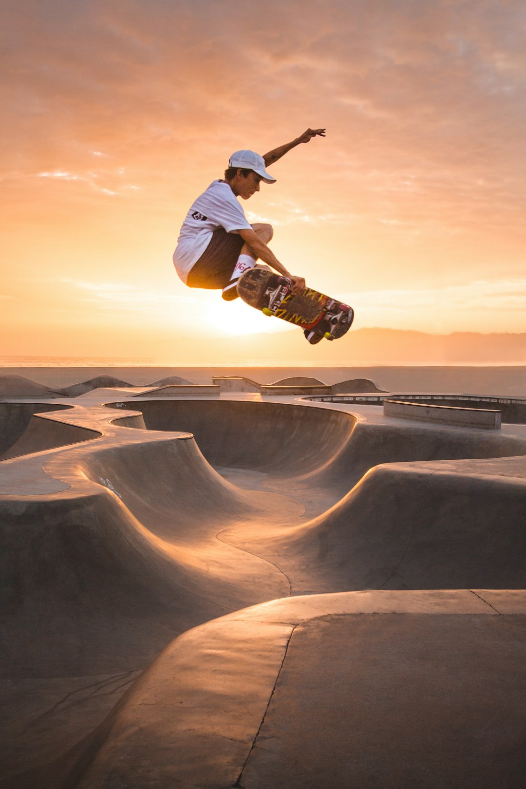 man in white t-shirt and brown pants riding skateboard on brown sand during daytime