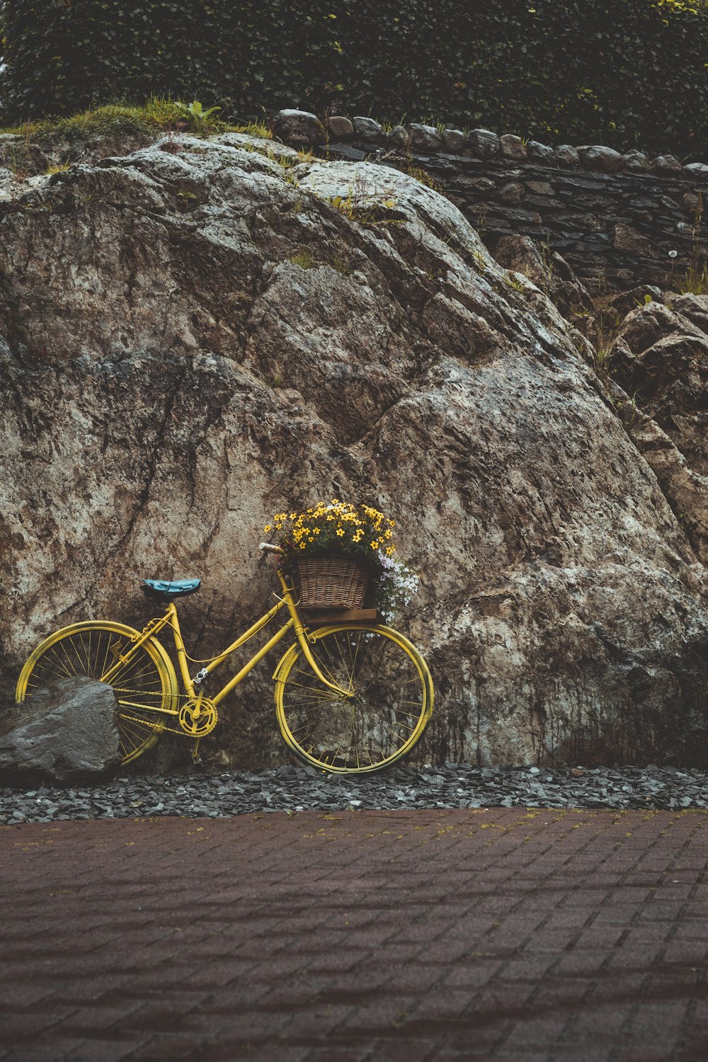 갈색 바위에 기대어 있는 노란 도시 자전거