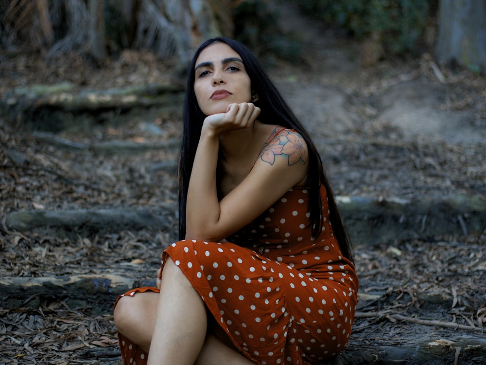 woman in red and white polka dot dress sitting on ground