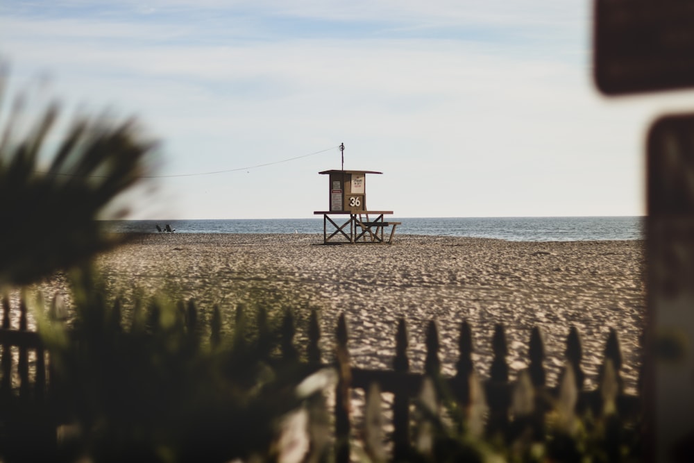 black wooden lifeguard tower on beach during daytime