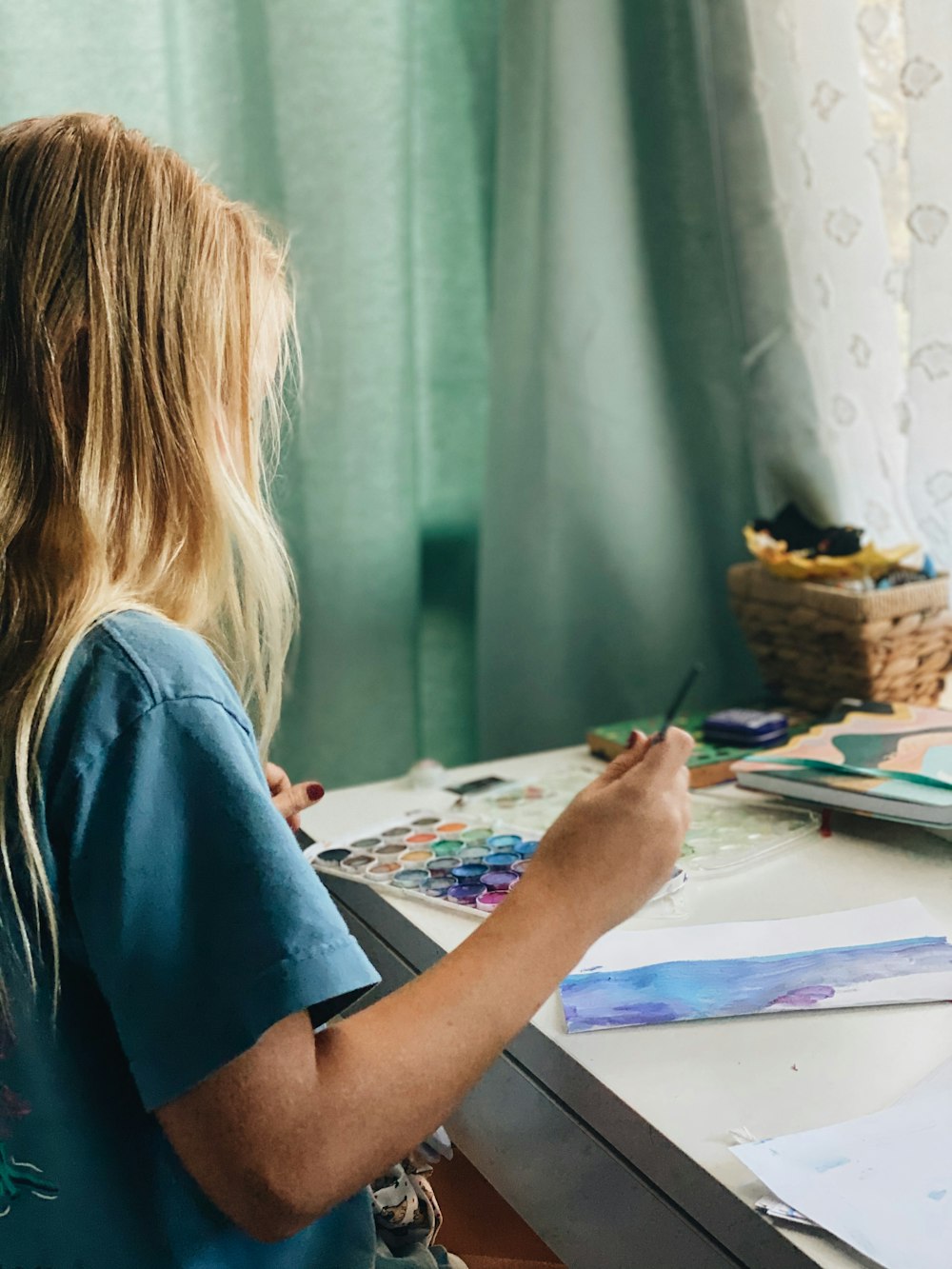 woman in blue shirt painting on white paper