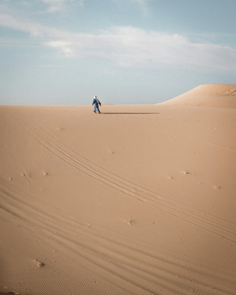 Person in schwarzer Jacke geht tagsüber durch die Wüste