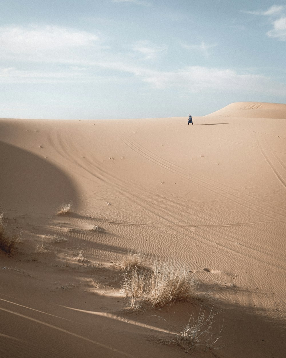 person walking on sand dunes during daytime