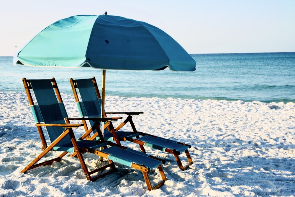 Dos sillas plegables de madera marrón en la playa durante el día