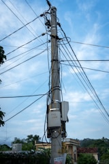 A technician installing broadband equipment on a utility pole in a suburban neighborhood.