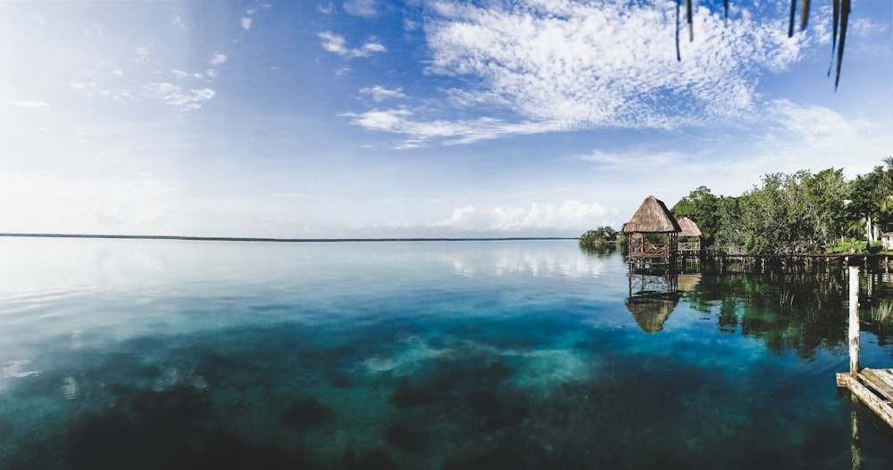 brown wooden house on body of water under blue sky during daytime