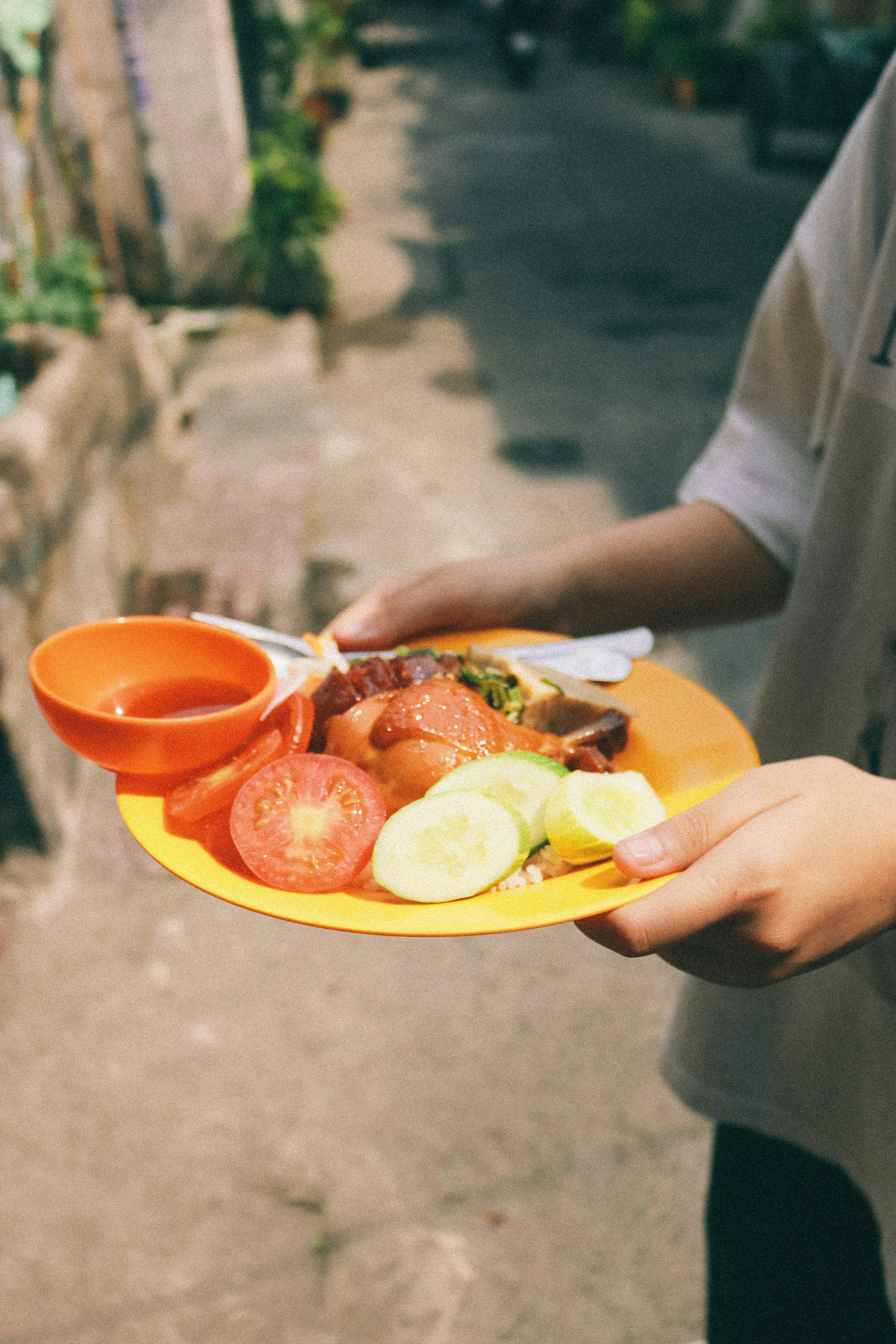 person holding yellow plate with sliced tomato and lettuce