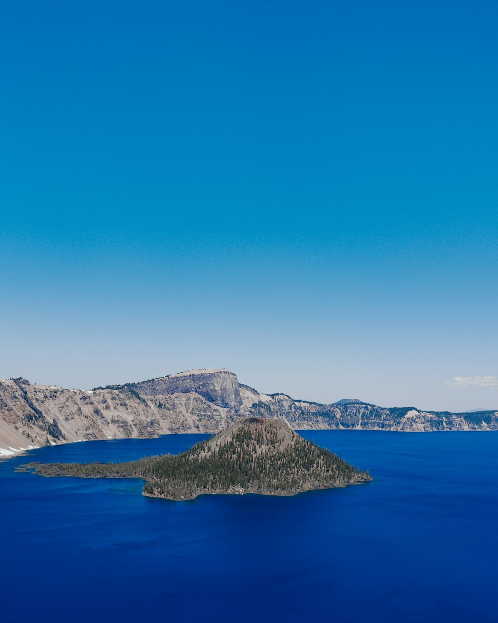 blue sea near mountain under blue sky during daytime