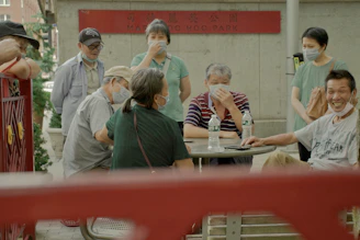 Masked volunteers distributing water bottles to people sitting on city sidewalks.