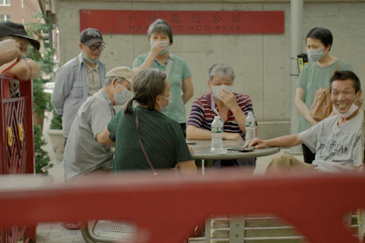 Masked volunteers distributing water bottles to people sitting on city sidewalks.