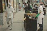 Group of people walking along a city street with trash bags and gloves.