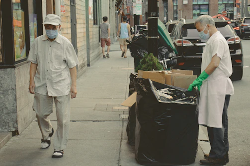 Group of people walking along a city street with trash bags and gloves.