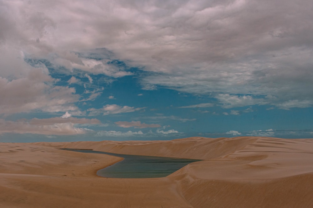 arena marrón bajo el cielo azul y nubes blancas durante el día