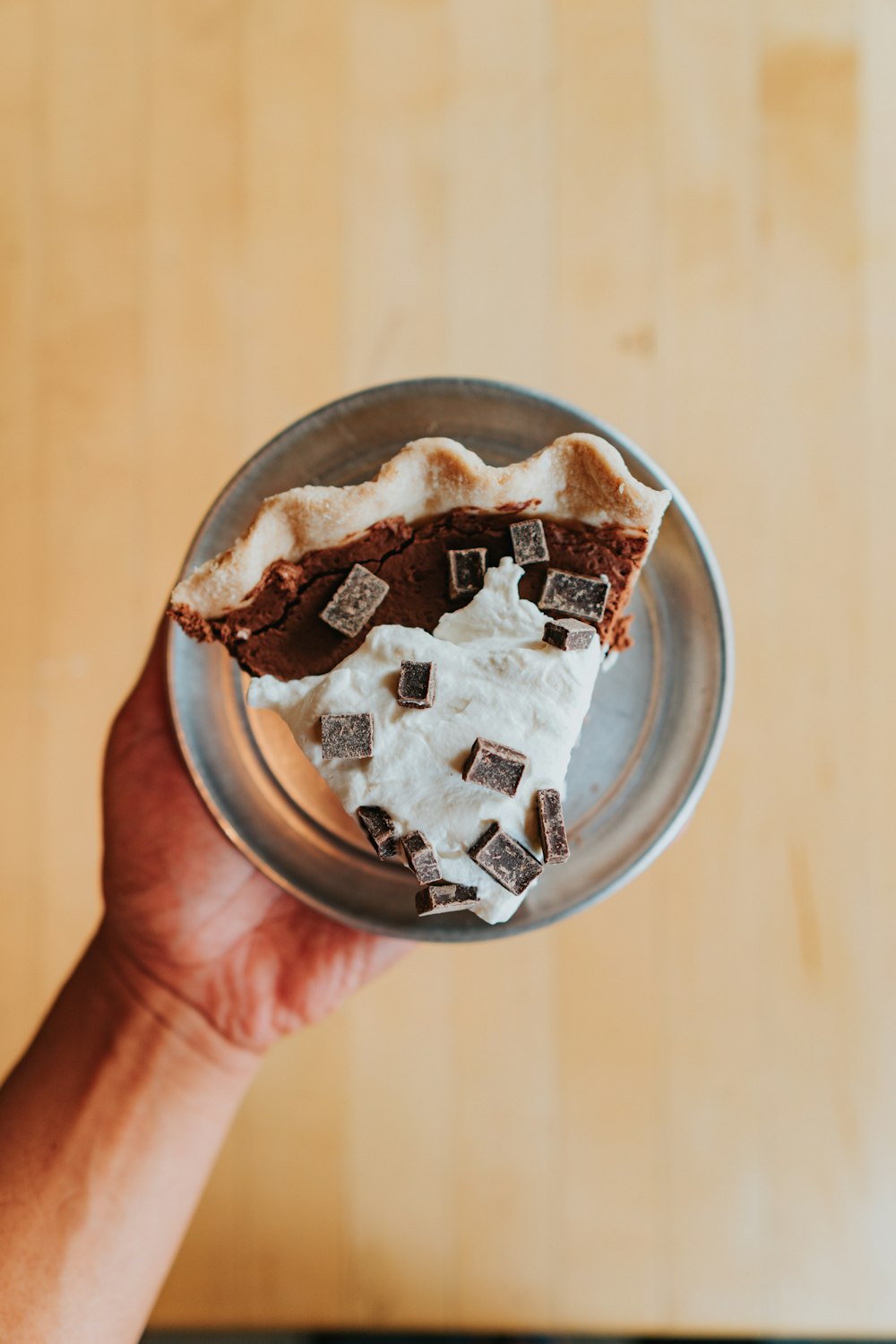 person holding stainless steel round bowl with chocolate cake