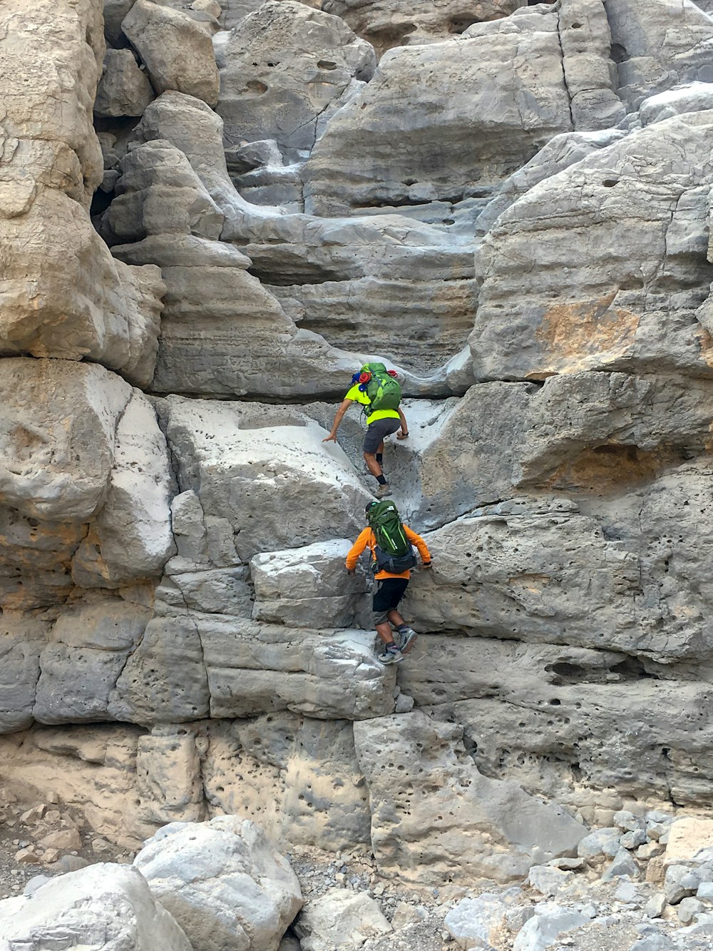 Uomo in giacca verde che si arrampica sulla montagna rocciosa durante il giorno