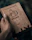 Close-up of hands holding the CJP manifesto notebook with a bold saffron cover