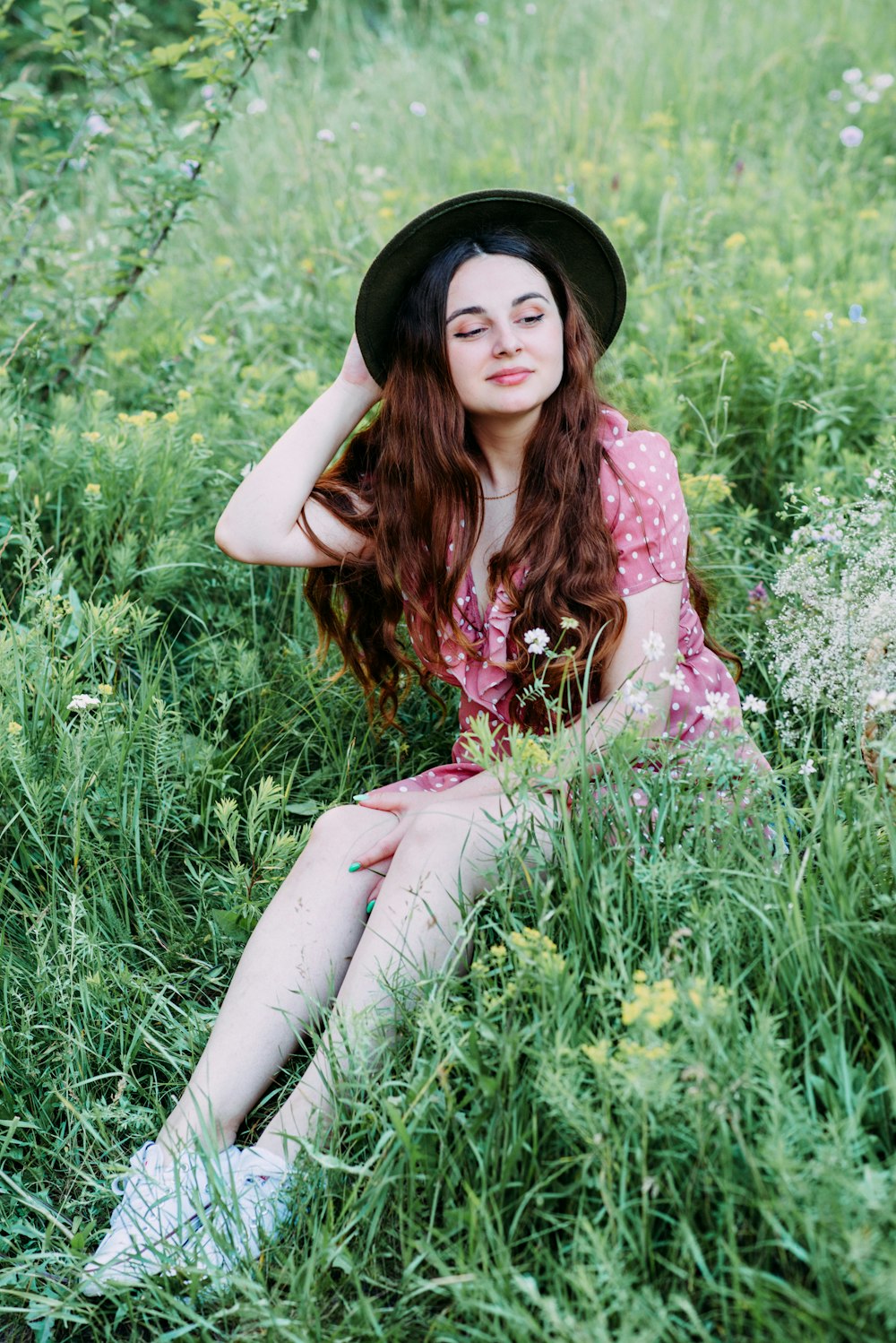 woman in white and pink floral dress sitting on green grass during daytime