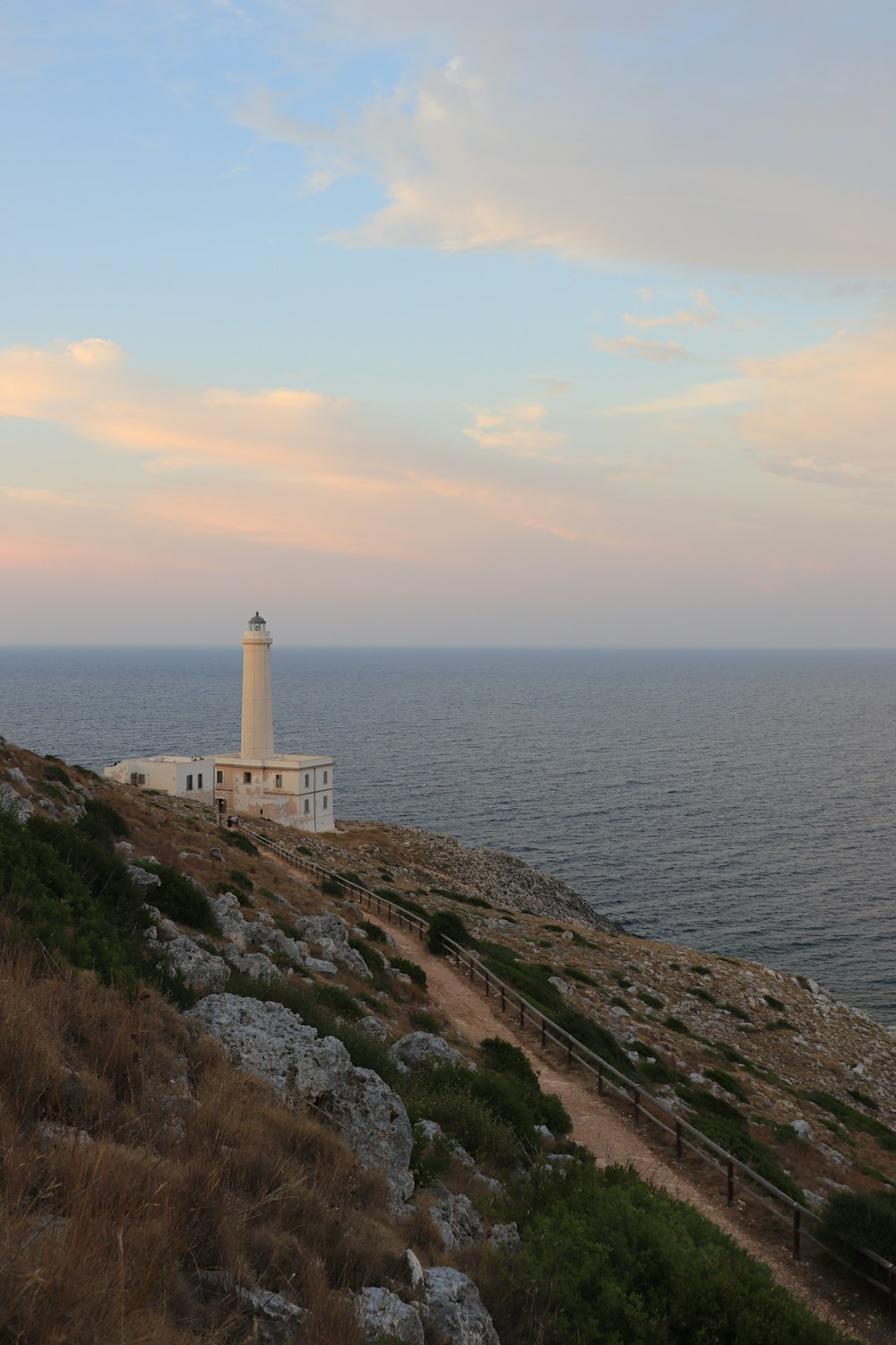 white lighthouse near body of water during sunset