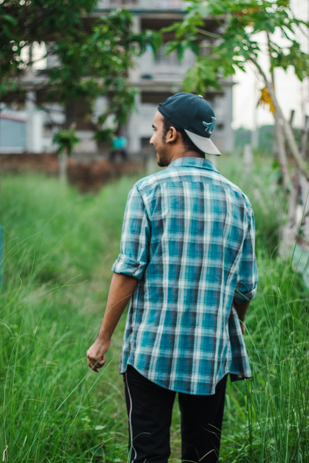 man in blue and white plaid button up shirt standing on green grass field during daytime