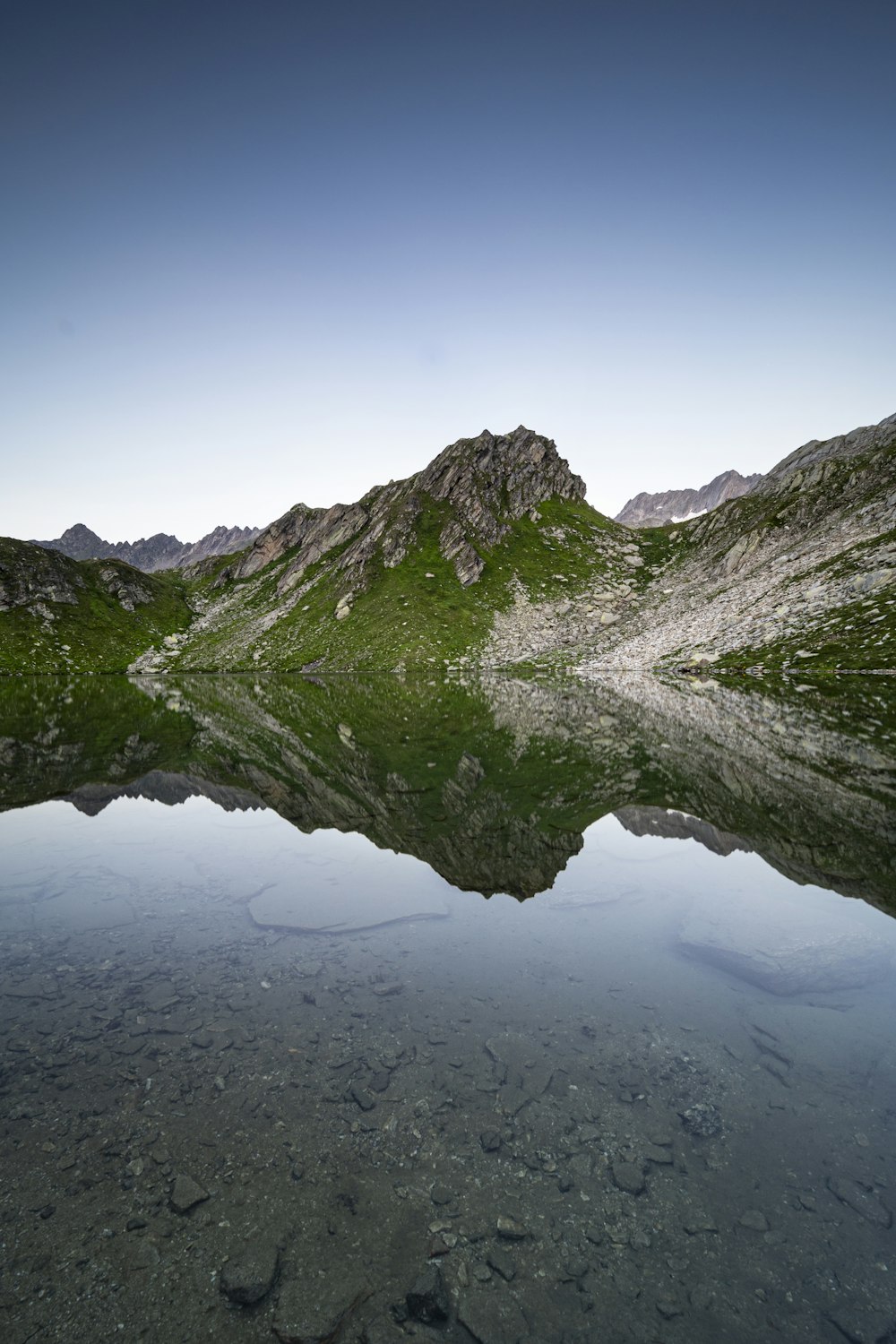 green and gray mountain beside body of water during daytime