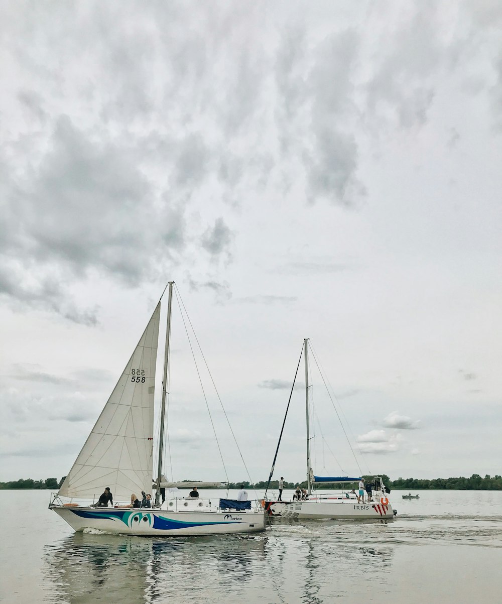 white sail boat on sea under cloudy sky during daytime