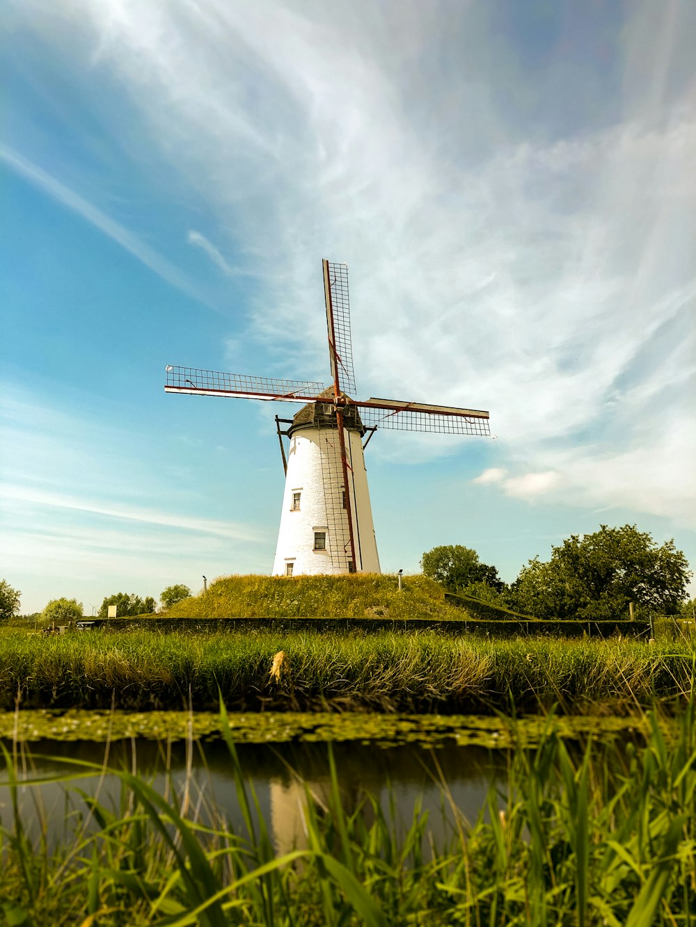 white and brown windmill on green grass field under blue sky during daytime