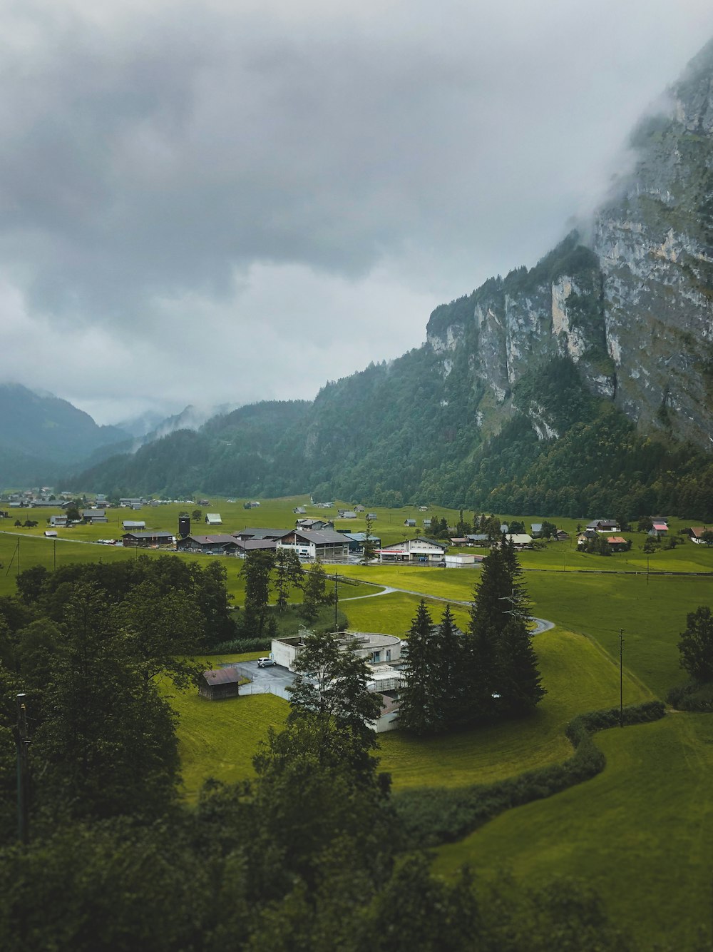 green grass field near mountain under cloudy sky during daytime