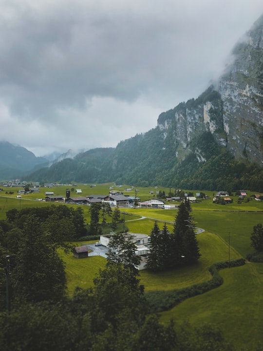 green grass field near mountain under cloudy sky during daytime in 3862 Innertkirchen Switzerland