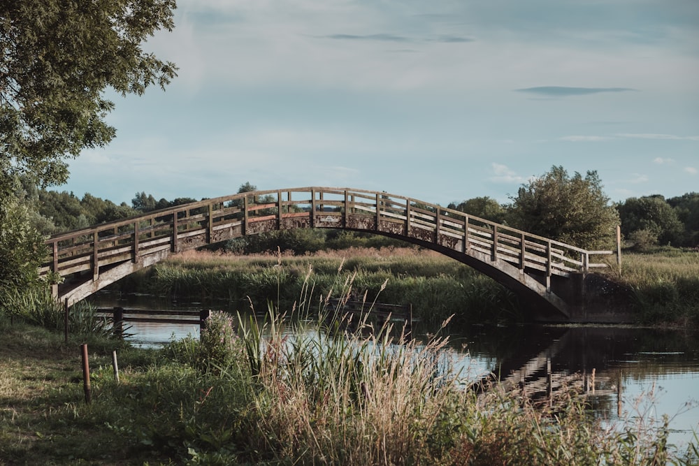 brown wooden bridge over river under white clouds during daytime