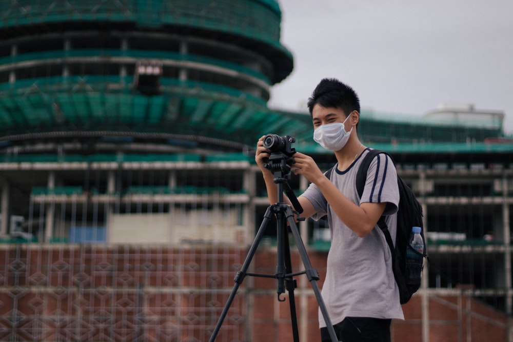 man in white crew neck t-shirt using black dslr camera