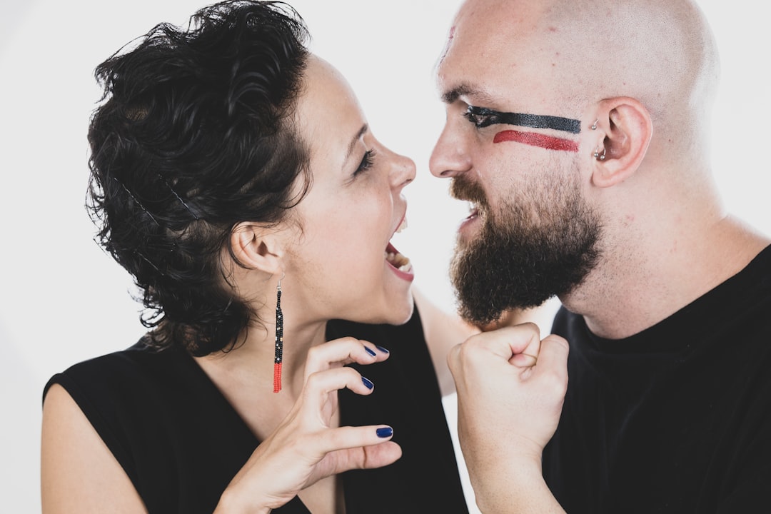 man in black shirt holding black smartphone beside woman in black shirt