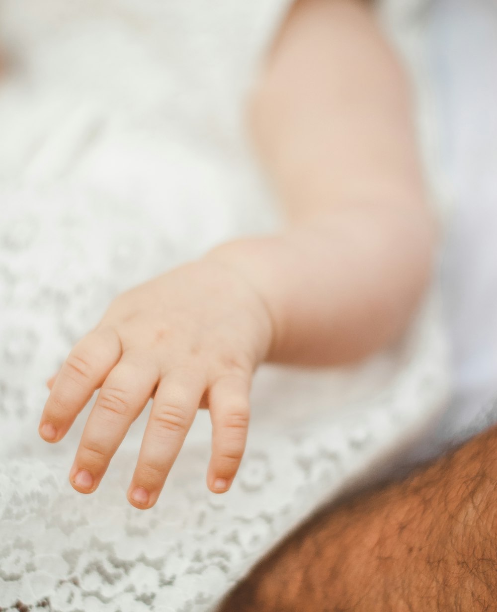 persons hand on white textile