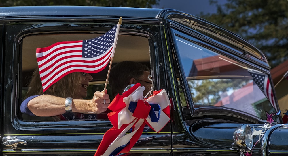 woman in car holding us a flag