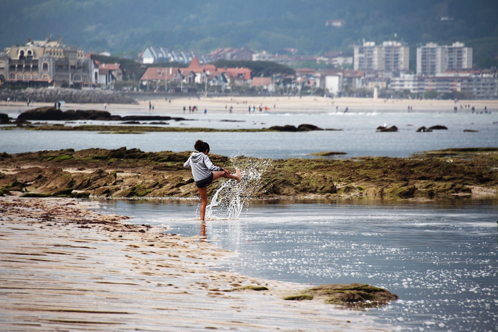 man in white shirt and black shorts standing on seashore during daytime