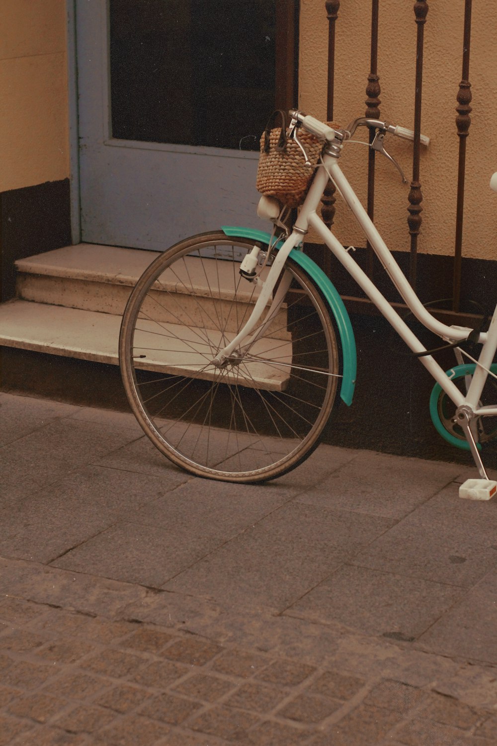 Bicicleta urbana verde azulado estacionada junto a un muro de concreto marrón