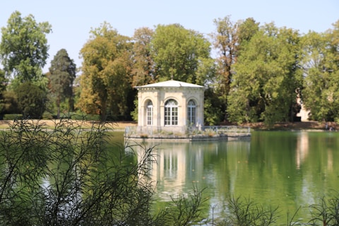 white concrete building near green trees and river during daytime