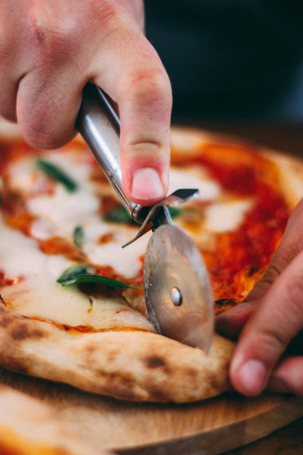 persona sosteniendo un cuchillo de acero inoxidable cortando pizza