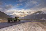 A rugged truck towing the HF trailer along a winding mountain road under a clear blue sky.