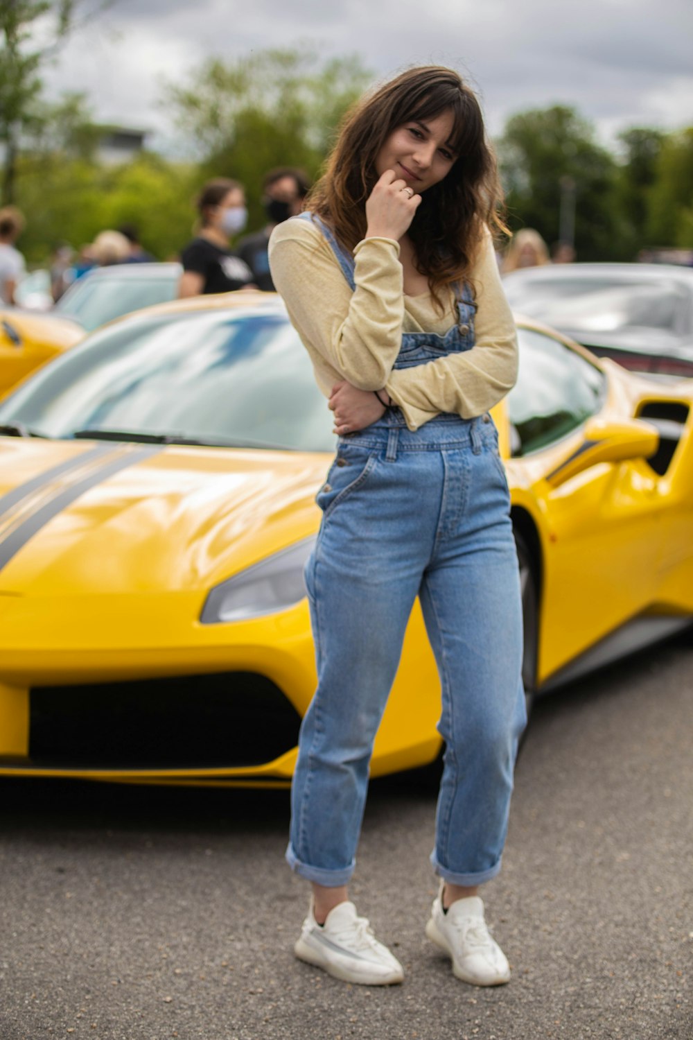 woman in gray long sleeve shirt and blue denim jeans standing beside yellow car during daytime
